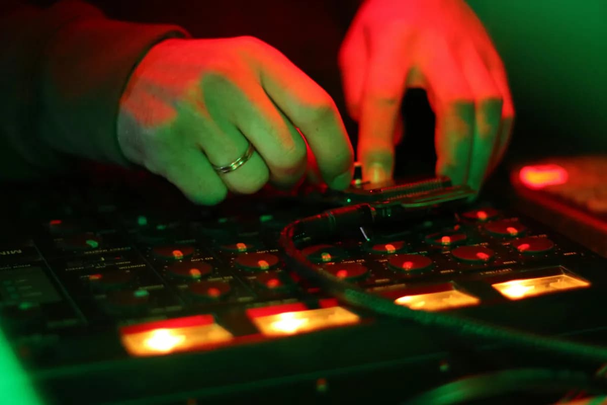 Hands working at a control panel lit in red and green