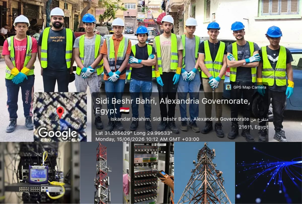 A field team in hard hats and safety vests on a street in Alexandria, with the camera location stamp, above a row of telecom towers, racks and fibre