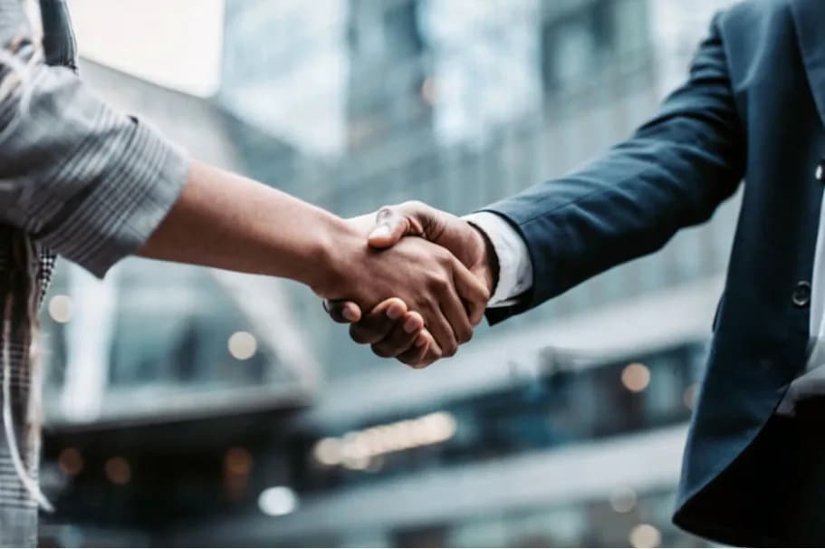 Two businessmen shaking hands outside a glass building
