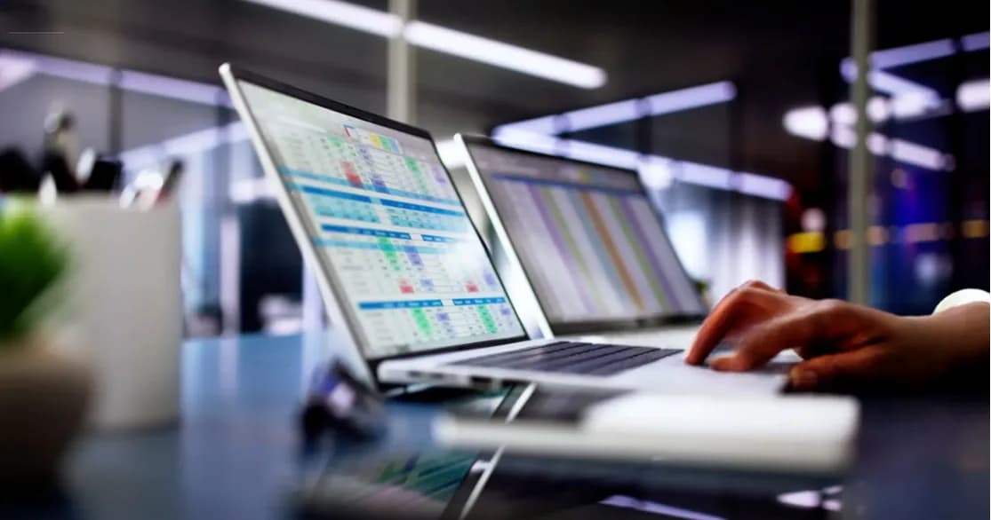 Spreadsheets open on two laptops in an office