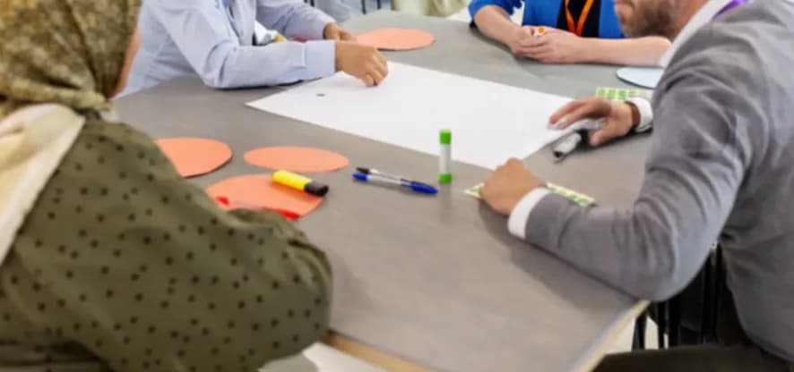 Participants around a table with markers and paper circles in a workshop