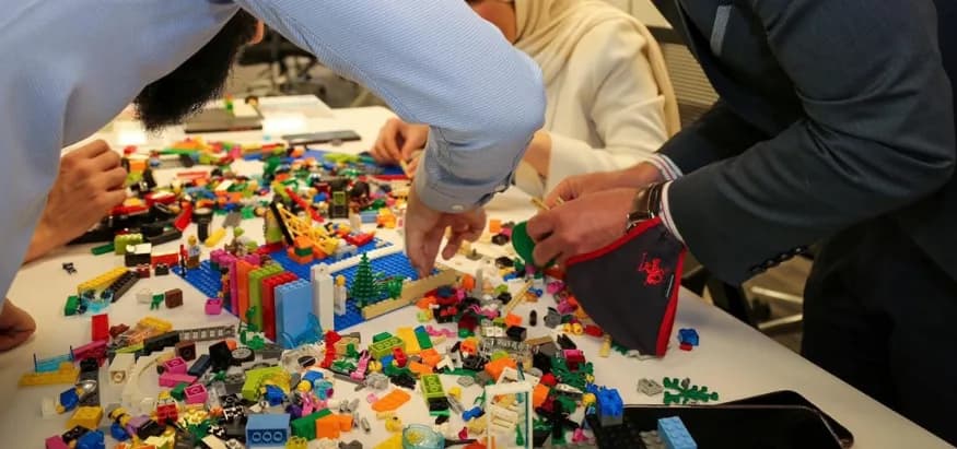 Hands building with coloured bricks on a workshop table